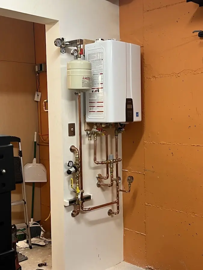 Plumbing technician inspecting water heater connections in Belle Plaine